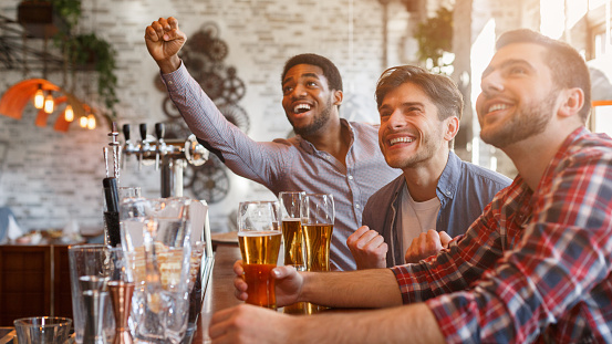 Football fans drinking beer, celebrating victory at sport bar