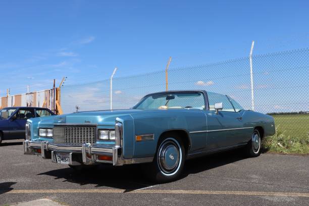 Fosston, USA - August 27, 2011:  A 1973 Cadillac Eldorado Convertible with a personalized 73DREAM Minnesota Collector license plate.  The car is on display at a classic car show being held on the grounds of a public school, with the school building in the background.  There is a woman standing in front of the car and reflections of people and additional vehicles in the side of the Cadillac.