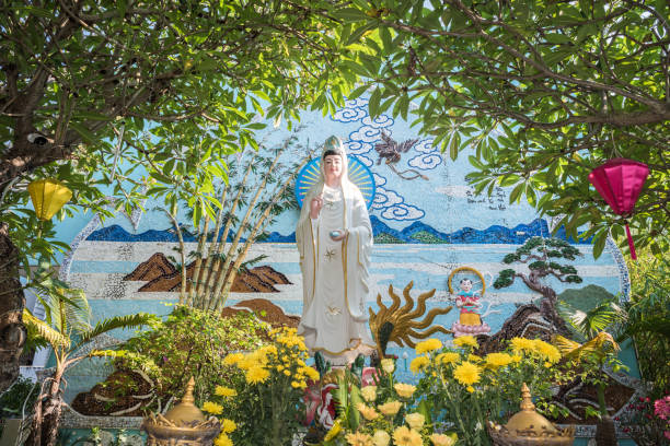 Quan Am statue in Da Nang Da Nang, Vietnam - March 25, 2019: Lady Buddha (Quan Am, known as Guanyin in China) and colorful mosaic among flowers in Chua Tan Ninh Buddhist temple. kannon bosatsu stock pictures, royalty-free photos & images