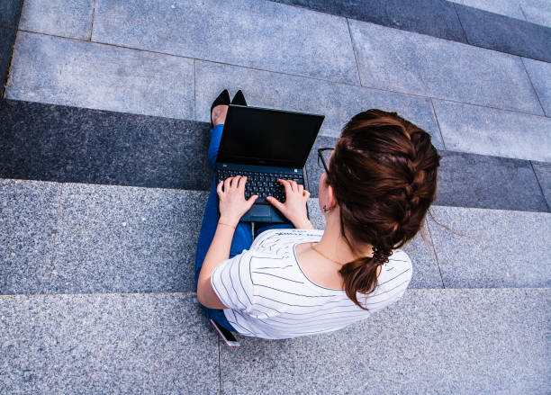 istock girl with notebook sitting on the gray steps 1152985414