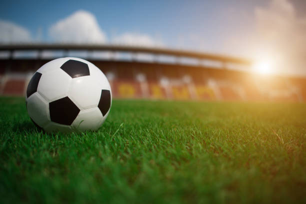 istock soccer ball on grass with stadium background 1152986764