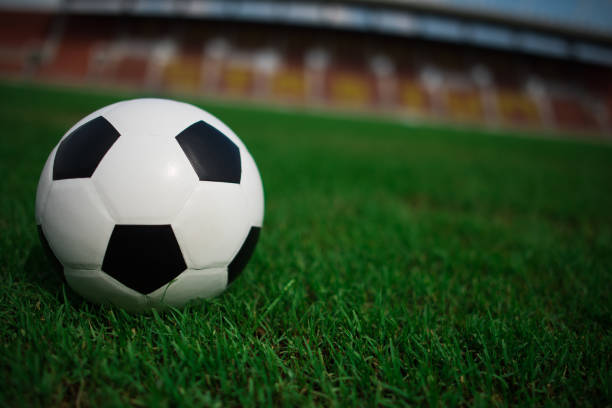 istock soccer ball on grass with stadium background 1152986771