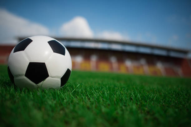 istock soccer ball on grass with stadium background 1152986774