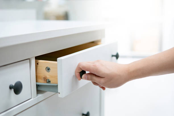 Male hand opening drawer on white cabinet Male hand pulling and opening drawer on white wooden cabinet. Home furniture and decoration shopping concept open drawer stock pictures, royalty-free photos & images