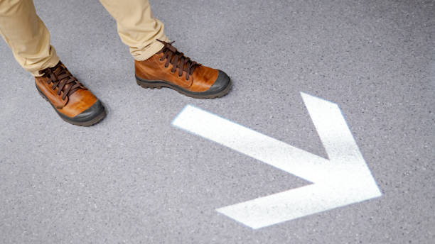 istock Feet stepping over arrowhead sign on the floor 1152994009