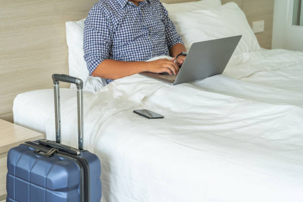 istock Businessman working with laptop on bed next to suitcase 1152994825