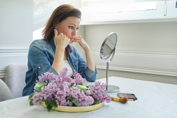 portrait de femme mûre avec le miroir de maquillage massant son visage et le cou, belle femelle 40 années vieux - 45 49 years photos et images de collection