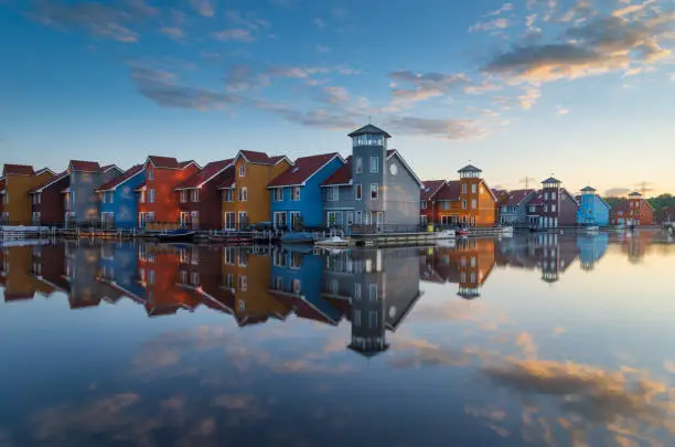 Tranquil sunrise at colorful wooden houses in a small marina in the Netherlands.  Living at the waterfront in Groningen.