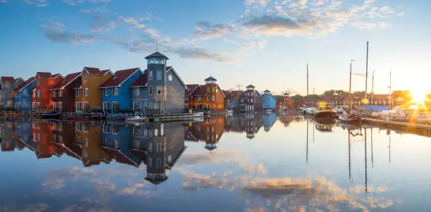 Tranquil sunrise at colorful wooden houses in a small harbor in the Netherlands.  Living at the waterfront in Groningen.