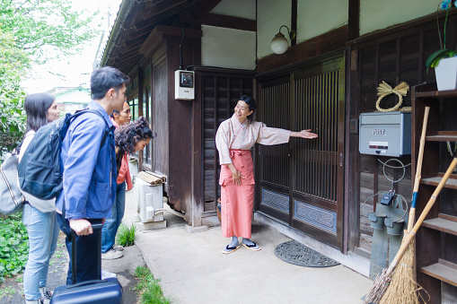 A female owner of a Japanese inn is welcoming multi-ethnic tourists from oversees.