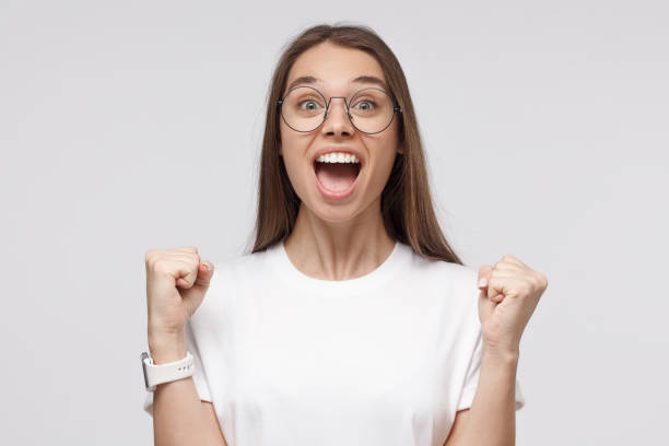 istock Young attractive woman shouting while her team win, raised both fist in victory gesture, isolated on gray background. Soccer fan concept 1153003839