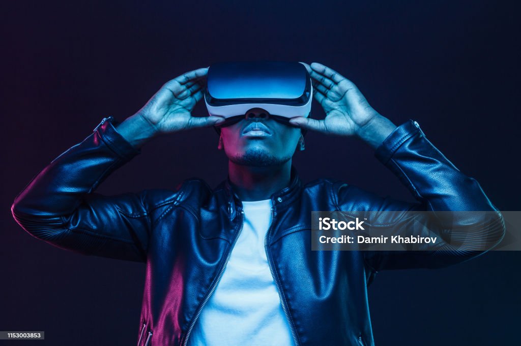 African american man in vr glasses, watching 360 degree video with virtual reality headset isolated on black background Virtual Reality Simulator Stock Photo