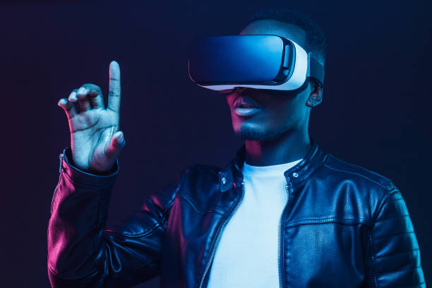 istock African american man in vr glasses, using virtual reality headset, trying to touch something with finger 1153003876