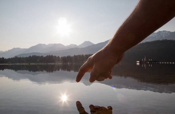 istock Man's hands come down to touch water surface at sunrise 1153005303