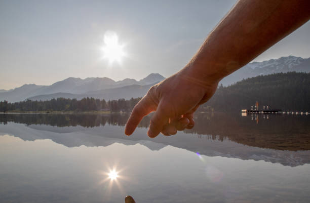 istock Man's hands come down to touch water surface at sunrise 1153005308