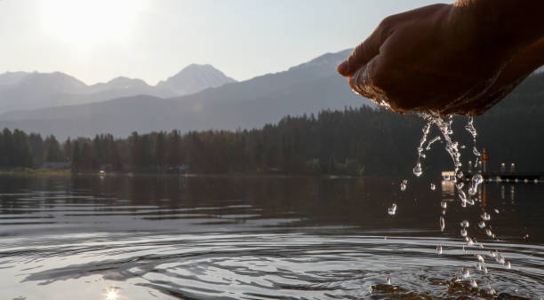 istock Man's hands come down to touch water surface at sunrise 1153005311