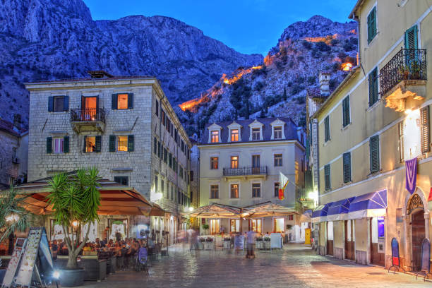 Kotor, Montenegro Scene in the medieval town of Kotor, Montenegro at twilight with the ancient city walls illuminated in the background mountains. montenegro stock pictures, royalty-free photos & images