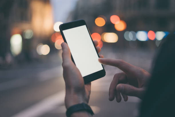 istock Closeup image of male hand holding smartphone with blank screen. Mockup ready for text message or content. Man's hands with cellphone. Empty display. Night street, bokeh light 1153010870