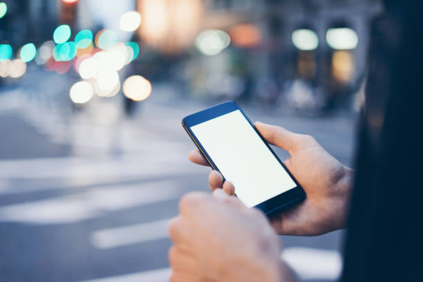 istock Closeup image of male hand holding smartphone with blank screen. Mockup ready for text message or content. Man's hands with cellphone. Empty display. Night street, bokeh light 1153010877