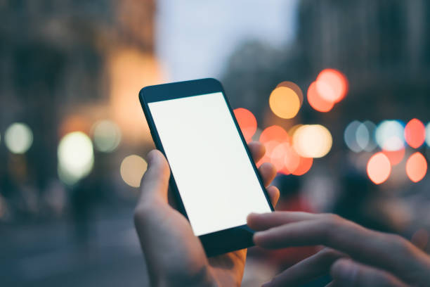 istock Closeup image of male hand holding smartphone with blank screen. Mockup ready for text message or content. Man's hands with cellphone. Empty display. Night street, bokeh light 1153010902