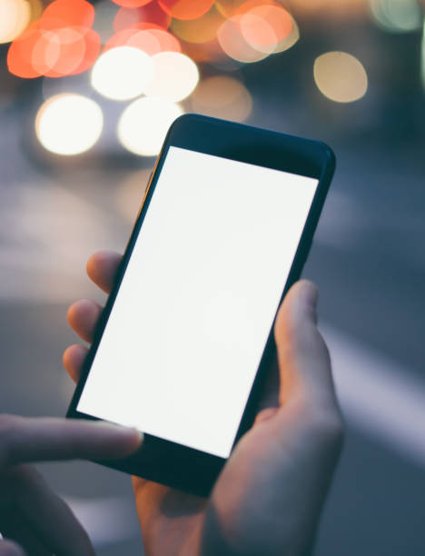 istock Closeup image of male hand holding smartphone with blank screen. Mockup ready for text message or content. Man's hands with cellphone. Empty display. Night street, bokeh light 1153010924