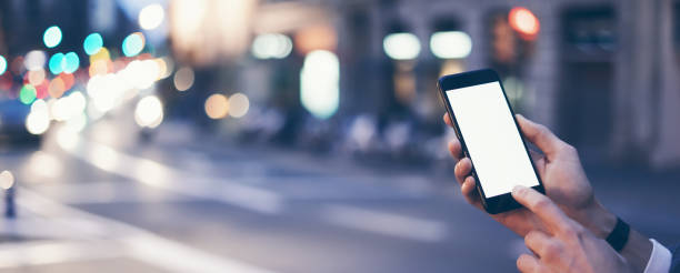 istock Closeup image of male hand holding smartphone with blank screen. Mockup ready for text message or content. Man's hands with cellphone. Empty display. Night street, bokeh light 1153010941