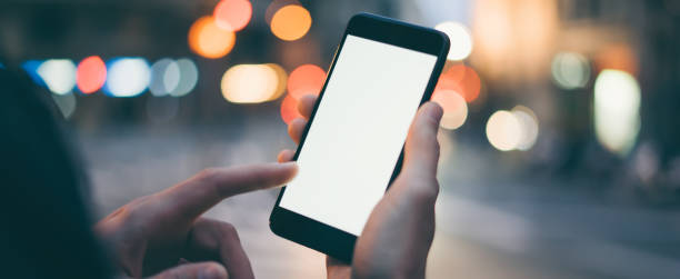 istock Closeup image of male hand holding smartphone with blank screen. Mockup ready for text message or content. Man's hands with cellphone. Empty display. Night street, bokeh light 1153010946