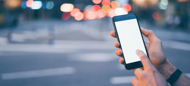istock Closeup image of male hand holding smartphone with blank screen. Mockup ready for text message or content. Man's hands with cellphone. Empty display. Night street, bokeh light 1153010955