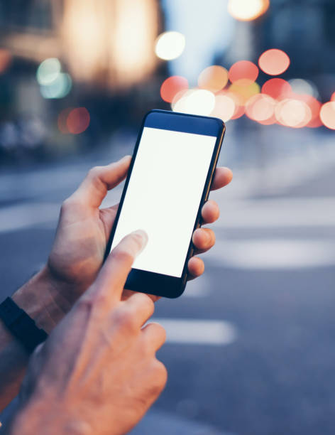 istock Closeup image of male hand holding smartphone with blank screen. Mockup ready for text message or content. Man's hands with cellphone. Empty display. Night street, bokeh light 1153010961
