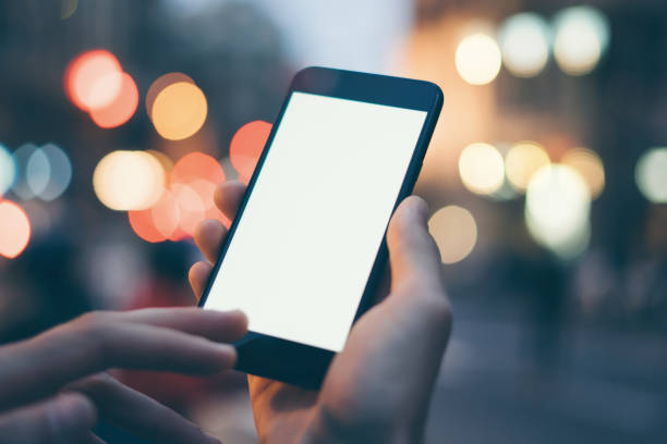istock Closeup image of male hand holding smartphone with blank screen. Mockup ready for text message or content. Man's hands with cellphone. Empty display. Night street, bokeh light 1153010963