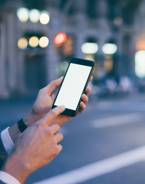 istock Closeup image of male hand holding smartphone with blank screen. Mockup ready for text message or content. Man's hands with cellphone. Empty display. Night street, bokeh light 1153010980
