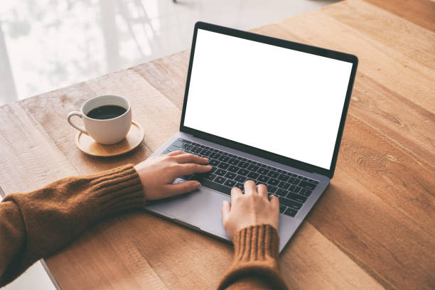 istock Mockup image of a woman using and typing on laptop computer keyboard with blank white desktop screen with coffee cup on wooden table 1153011406