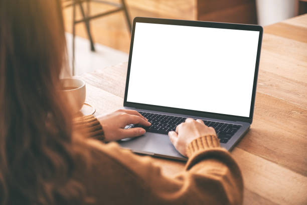 istock Mockup image of a woman using and typing on laptop computer keyboard with blank white desktop screen with coffee cup on wooden table 1153011420