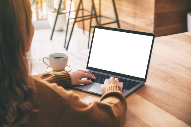 istock Mockup image of a woman using and typing on laptop computer keyboard with blank white desktop screen with coffee cup on wooden table 1153011504