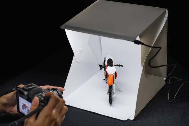фотограф-любитель, работающий на беззерковой камере для съемки модели motrocycle в мини-лайтбоксе - lightbox стоковые фото и изображения