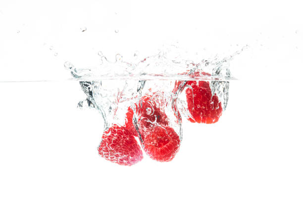 frische himbeeren fallen in wasser auf weißem hintergrund - falling fruit berry fruit raspberry stock-fotos und bilder
