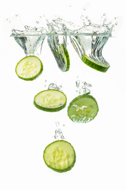 istock Sliced cucumber splashing water isolated on white background. 1153017779
