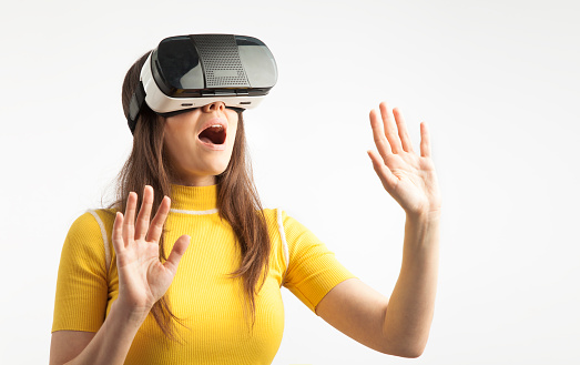 Young woman wearing virtual reality device over white background. Virtual Reality digital concept touch screen.
