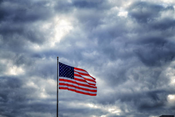 istock American flag flapping in dark ominous sky 1153019648