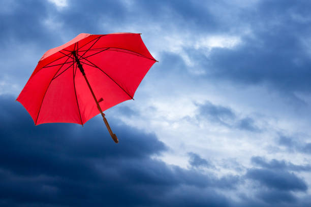 red umbrella under the cloud on sky blue background.