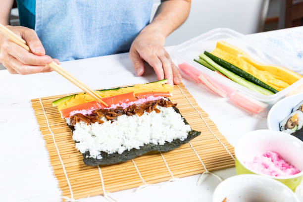 istock Woman prepares sushi rolls, hands closeup 1153019874