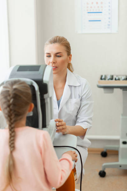 istock Experienced blonde oculist dealing with little kid while diagnosing 1153021717