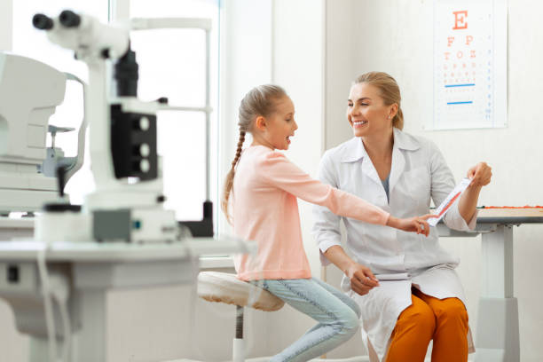 istock Active young girl pointing on elements of eye presented on a paper 1153021721