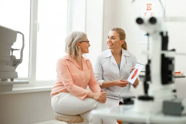 Important conversation. Beaming long-haired woman having appointment with older patient and discussing her issues