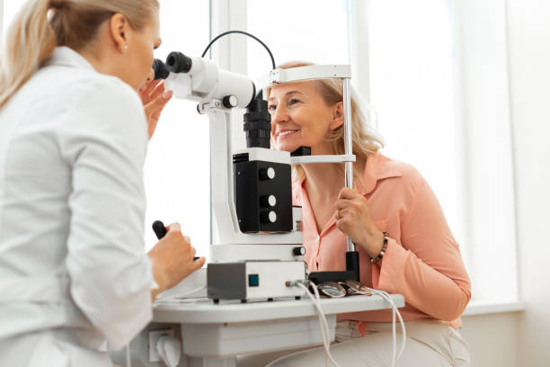Smiling good-looking senior lady sitting in front of professional oculist stock photo