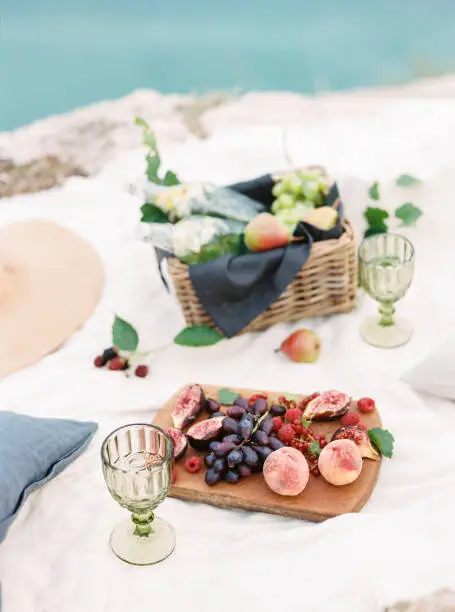 Delicious and healthy picnic near the sea. Natural lemonade and fresh fruits lie on a boho-style rug.