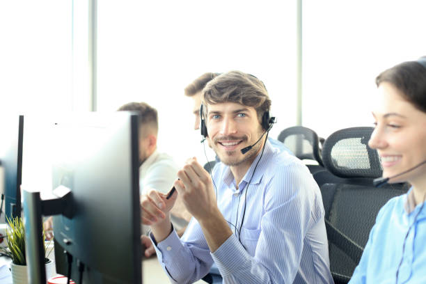 istock Portrait of call center worker accompanied by his team. Smiling customer support operator at work. 1153023980