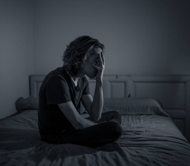istock Devastated millennial man crying sad feeling hurt and hopeless suffering Depression. Depressed teenager victim of bullying or abuse sitting on bed alone in despair at night. In teenage Mental health. 1153024059