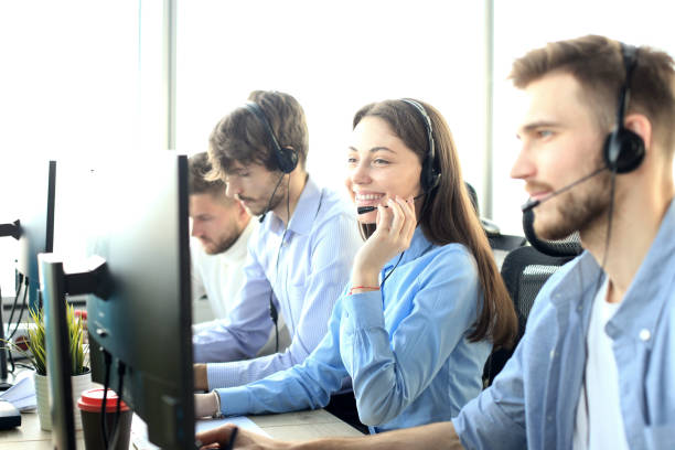 istock Portrait of call center worker accompanied by her team. Smiling customer support operator at work. 1153024246