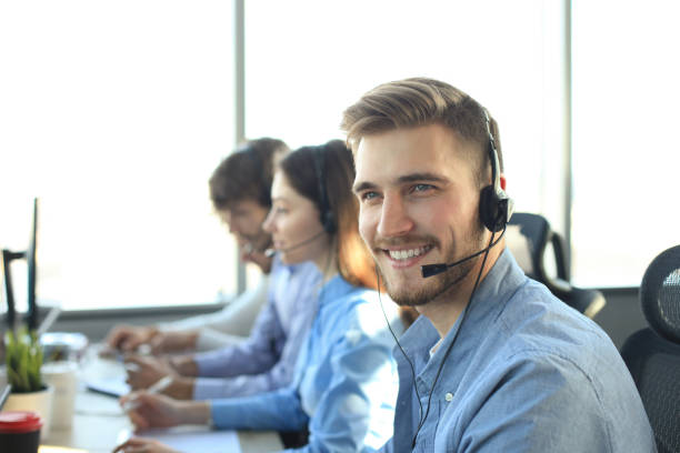 istock Portrait of call center worker accompanied by his team. Smiling customer support operator at work. 1153024299